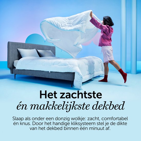 Femme en veste rose et chaussettes rouges, tenant une couette blanche matelassée au-dessus d'un lit. Texte : 'La couette la plus douce et la plus facile'.