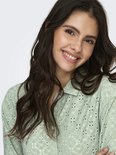 Close-up van model met lichtgroene blouse met broderie anglaise.