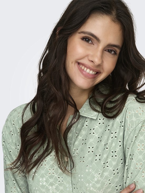 Close-up van model met lichtgroene blouse met broderie anglaise.