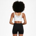 Achterkant van een vrouw met krullend haar in een witte sportbeha met rits en zwarte short.