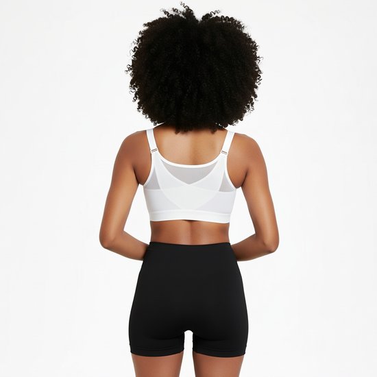Achterkant van een vrouw met krullend haar in een witte sportbeha met rits en zwarte short.