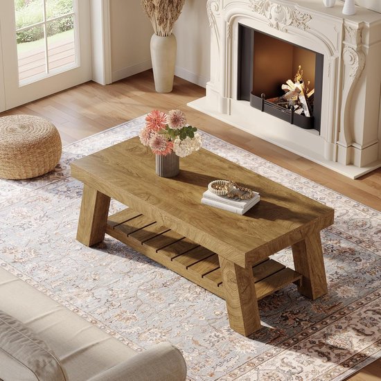 Houten salontafel met een open opbergruimte, met boeken en een vaas met bloemen.