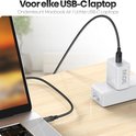 Witte 30W USB-C oplader laadt een laptop op met een zwarte gevlochten kabel.