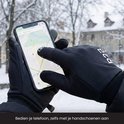Zwarte R2B handschoenen worden gedragen om een smartphone te bedienen in de sneeuw.