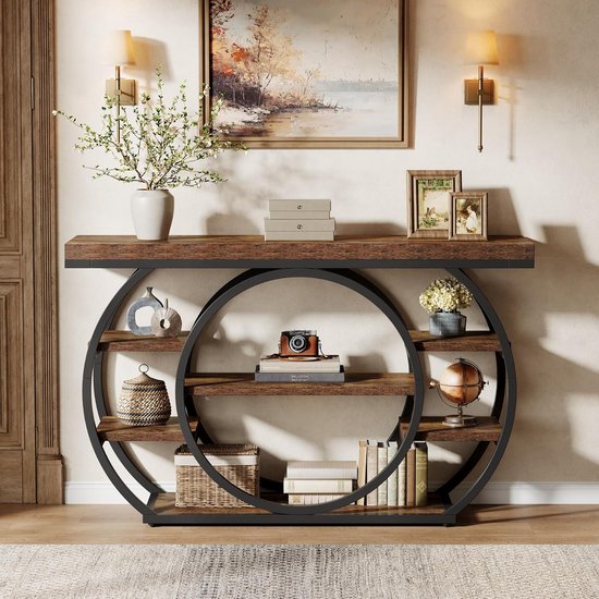 Bruine consoletafel met zwarte metalen cirkel-structuur, 5 open vakken, met decoraties zoals een camera, boeken, een wereldbol en fotolijsten.