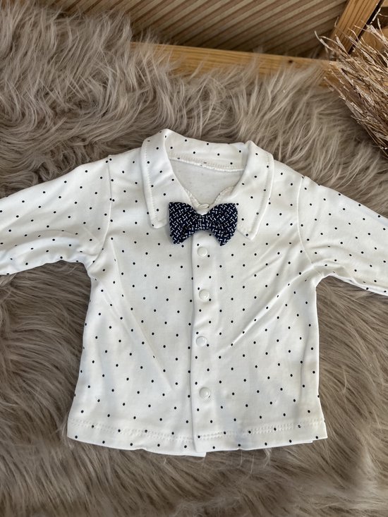 Wit poloshirt met zwarte stippen en een strikje met donkerblauwe print.