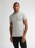 Grijze katoenen T-shirt met ronde hals en korte mouwen, gedragen door een man met een zwart logo op de linkerborst.