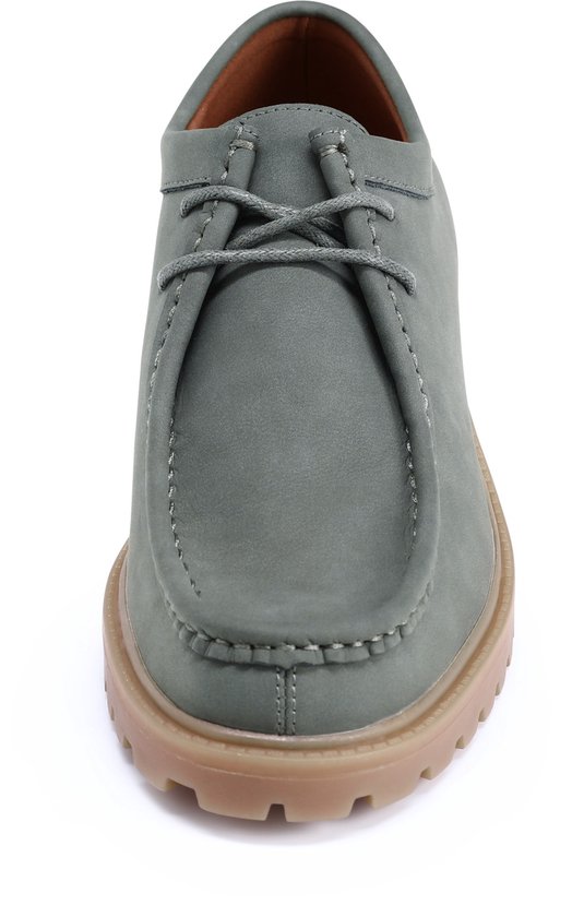 Vooraanzicht van een grijze suède loafer met vetersluiting en dikke bruine zool.