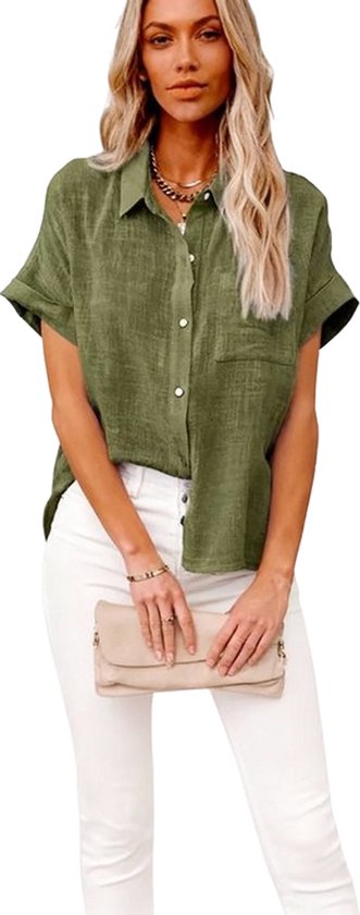 Model met groen linnen overhemd met korte mouwen, witte broek en beige tasje.
