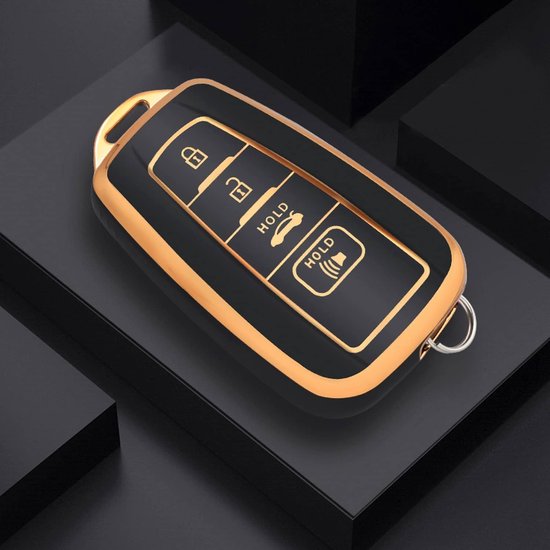 Zwarte autosleutelhoes met gouden rand en 4 knoppen, op een zwarte sokkel.