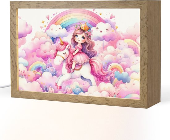 Een lamp met een prinses op een witte eenhoorn in een fantasiewereld met roze wolken en regenboog, omlijst door een houten kader.