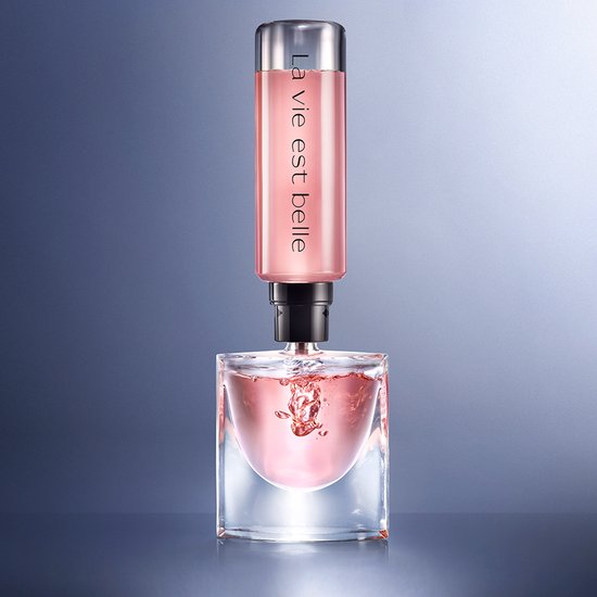 Een navulbare fles "La Vie est Belle" wordt in een glazen parfumfles gegoten.