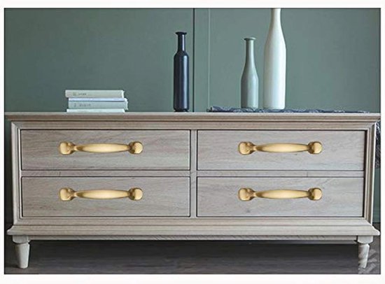 Vier matte gouden grepen op een houten ladekast.