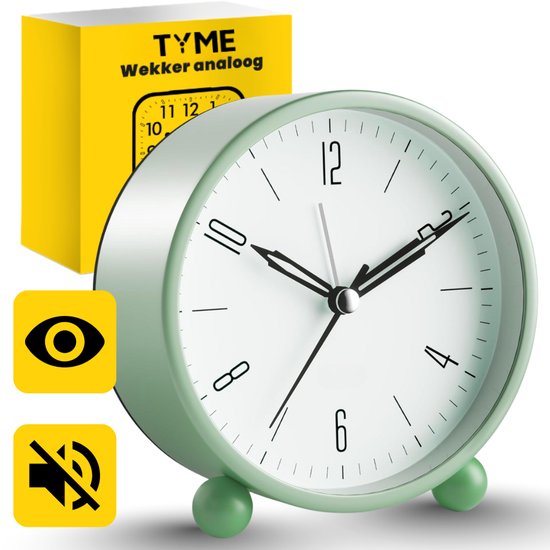 Lichtgroene analoge wekker met witte wijzerplaat, naast de gele verpakking.