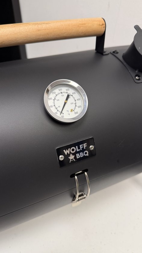 Zwarte draagbare BBQ van Wolff BBQ, detail van thermometer en logo, met houten handvat.