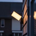 Zwarte wandlamp met sensor, verlicht de houten schutting 's avonds.