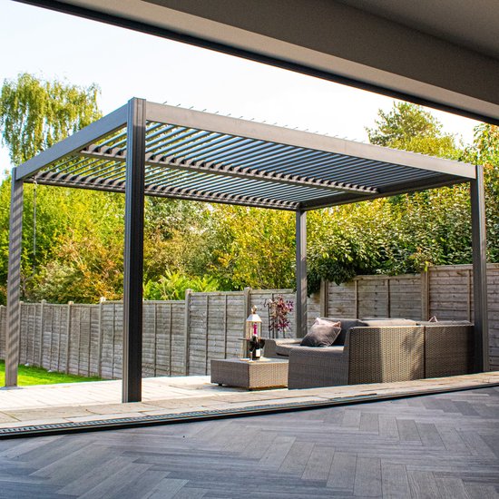 Pergola en aluminium gris avec toit à lamelles, mobilier de jardin et arbres verts en arrière-plan, vue de l'entrée.