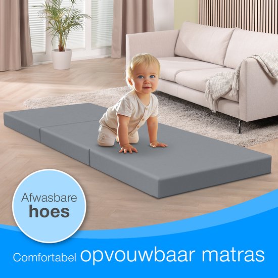 Grijze opvouwbare matras met afneembare hoes. Een baby kruipt op de matras.