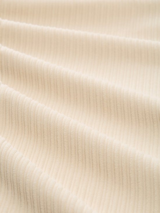 Detailopname van de beige corduroy stof met ribbels.
