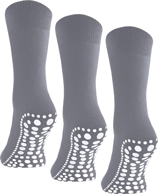Drie paar grijze huissokken met witte antislip stipjes op de zool, op zwarte achtergrond.