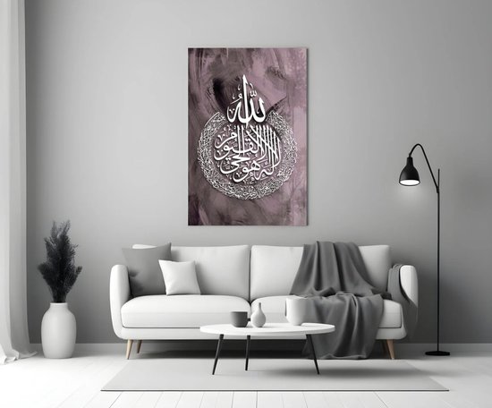 Un salon avec un canapé blanc, une table basse et un lampadaire, avec une peinture en verre de calligraphie islamique au mur.