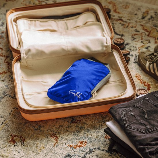 Donkerblauwe Sunflake packing cube in een open koffer met kleding ernaast.