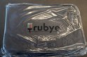 Boîte de rangement noire fermée pour diamants, emballée dans du plastique. Logo 'rubye' visible.