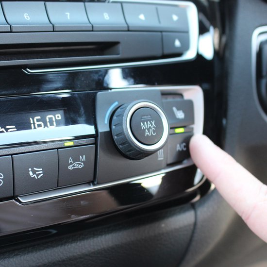 Vinger drukt op de A/C knop van een auto-airconditioningsysteem.