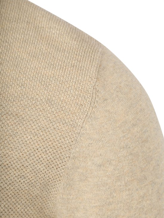 Detail van de beige trui, schouder en mouw.