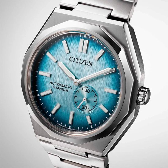 Close-up van een Citizen horloge met zilverkleurige titanium kast en band. Lichtblauwe wijzerplaat met geborstelde afwerking en datumvenster.