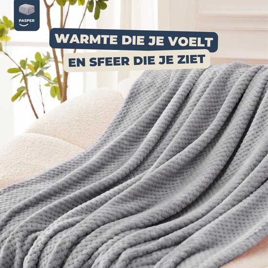 Grijze deken met wafelstructuur, geplaatst op een bank.