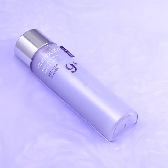 Lila Numbuzin No. 9 NAD+ PDRN Glow Boosting Toner fles met zilveren dop, op paarse ondergrond.
