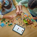 Twee meisjes bouwen aan de LEGO Friends-boomhut op een tafel.