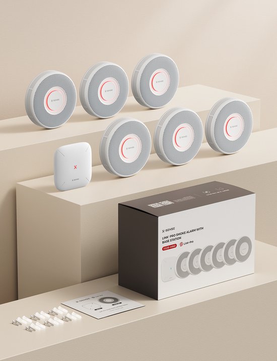 Zeven X-Sense rookmelders en een basisstation in een doos, met schroeven en handleiding.