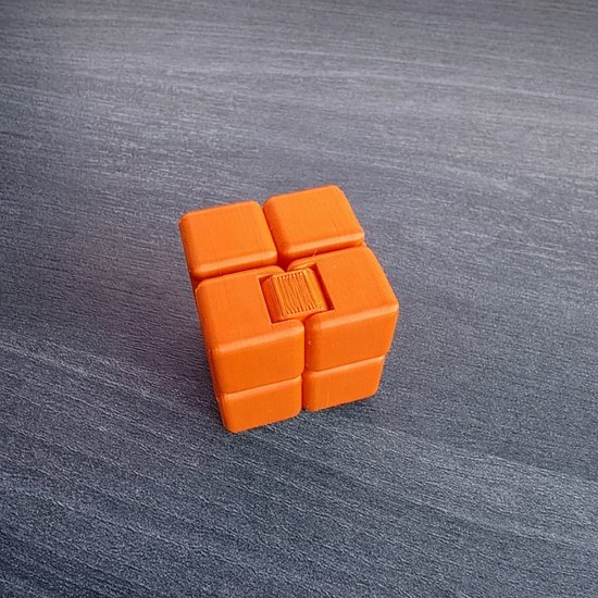 Oranje fidget cube met vier blokjes aan de boven- en onderkant, die je kunt draaien en vouwen.