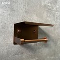 Geborsteld koperen toiletrolhouder met plateau aan grijze muur. Livinq logo.