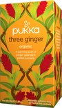 Pukka three ginger biologische thee verpakking met rode gemberbloemen en groene bladeren, op een oranje achtergrond.