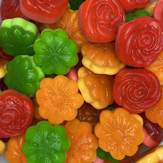 Een close-up van diverse snoepjes in de vorm van bloemen en rozen in rood, oranje en groen.