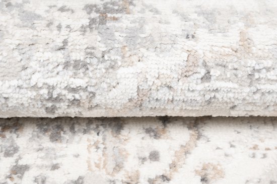 Gros plan sur la texture douce d'un tapis beige avec des motifs gris et bruns délavés.