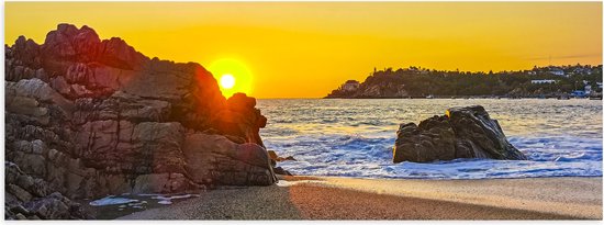 Poster Glanzend – Zon verdwijnend achter Rots op het Strand aan de Zee - 60x20 cm Foto op Posterpapier met Glanzende Afwerking