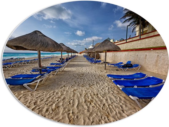 WallClassics - PVC Schuimplaat Ovaal - Blauwe Ligbedden op Strand met Rieten Parasols - 80x60 cm Foto op Ovaal (Met Ophangsysteem)