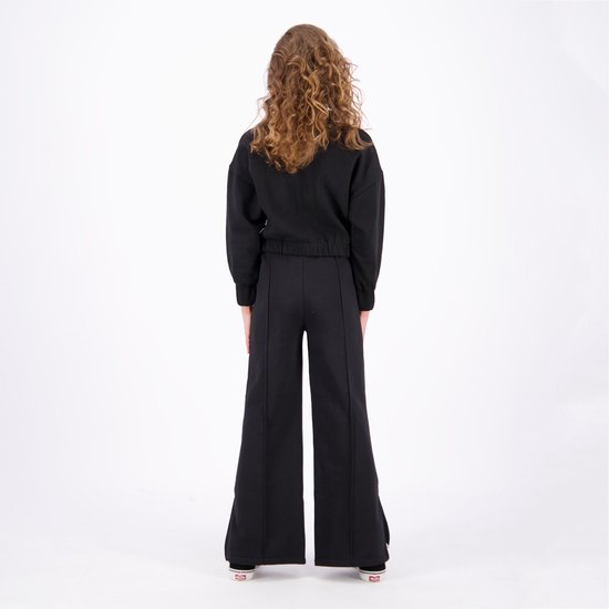 Meisje van achteren gezien in een zwarte set met een wijde broek.