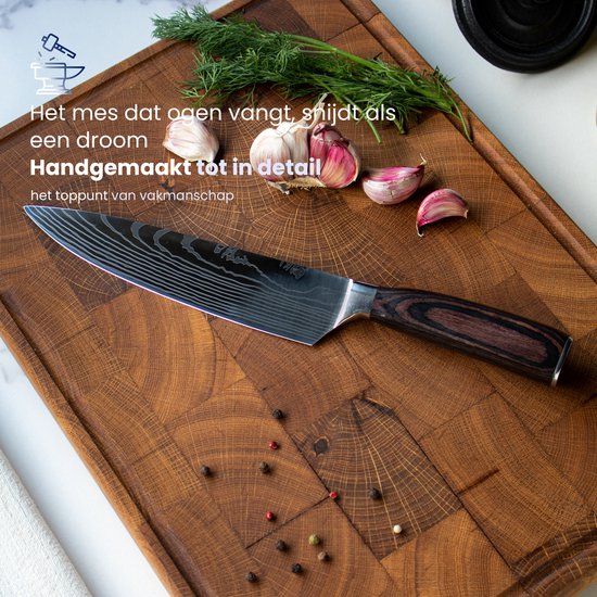 Couteau de chef à motif damas et manche en bois sombre, sur une planche à découper en bois avec de l'ail, de l'aneth et du poivre.