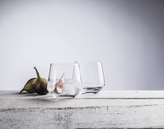 Deux verres à whisky en cristal, dont un rempli d'eau, de glace et d'une tranche de figue, sur un fond en bois à côté de deux figues.