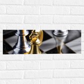 Muursticker - Foto van Drie Gouden en Zilveren Schaakstukken op Schaakbord - 60x20 cm Foto op Muursticker