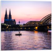 PVC Schuimplaat - Uitzicht op de Dom en Brug van Keulen tijdens de Avondzon in Duitsland - 50x50 cm Foto op PVC Schuimplaat (Met Ophangsysteem)