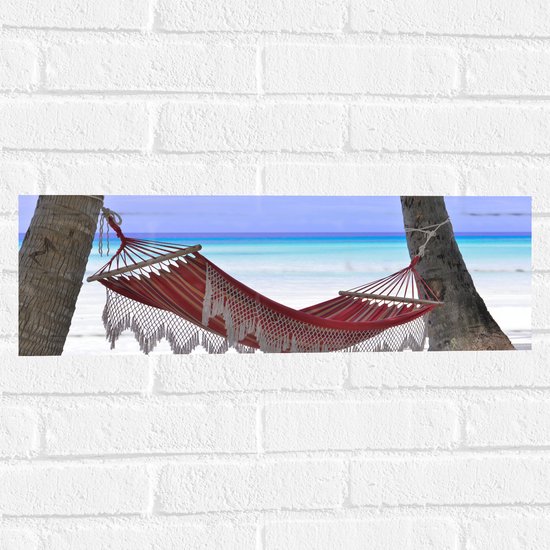 WallClassics - Muursticker - Rode Ibiza Hangmat op Tropisch Strand - 60x20 cm Foto op Muursticker
