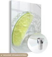 MuchoWow® Glasschilderij 90x120 cm - Schilderij acrylglas - Glas gin tonic met een schijfje limoen - Foto op glas - Schilderijen