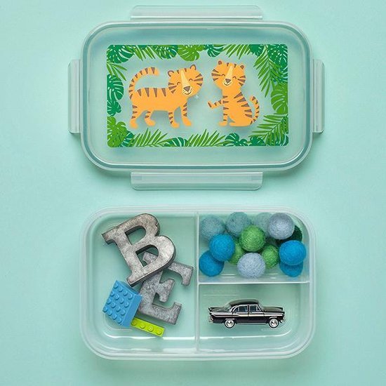 Boîte à pain transparente avec couvercle à motif tigre. Le fond est compartimenté et contient des lettres, une brique de construction, une voiture et des pompons.