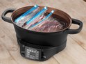 Zwarte multicooker met vlees in plastic zakken in water, bereid voor sous-vide.